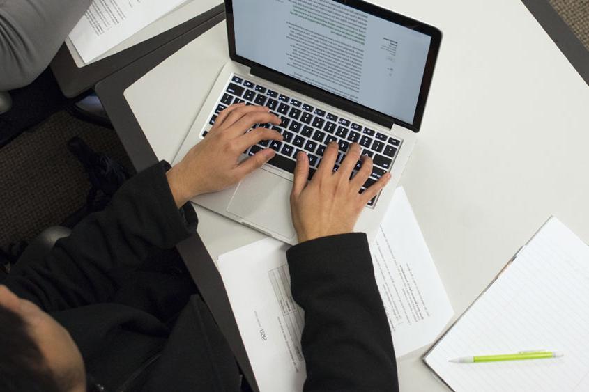 Student reading an article on his laptop while studying.