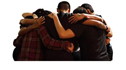 group of students stands in circle with arms around each other